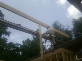 Carpenter setting a ridge beam over a new addition frame — Ice Dam Removal by Roofing Brothers in Gill