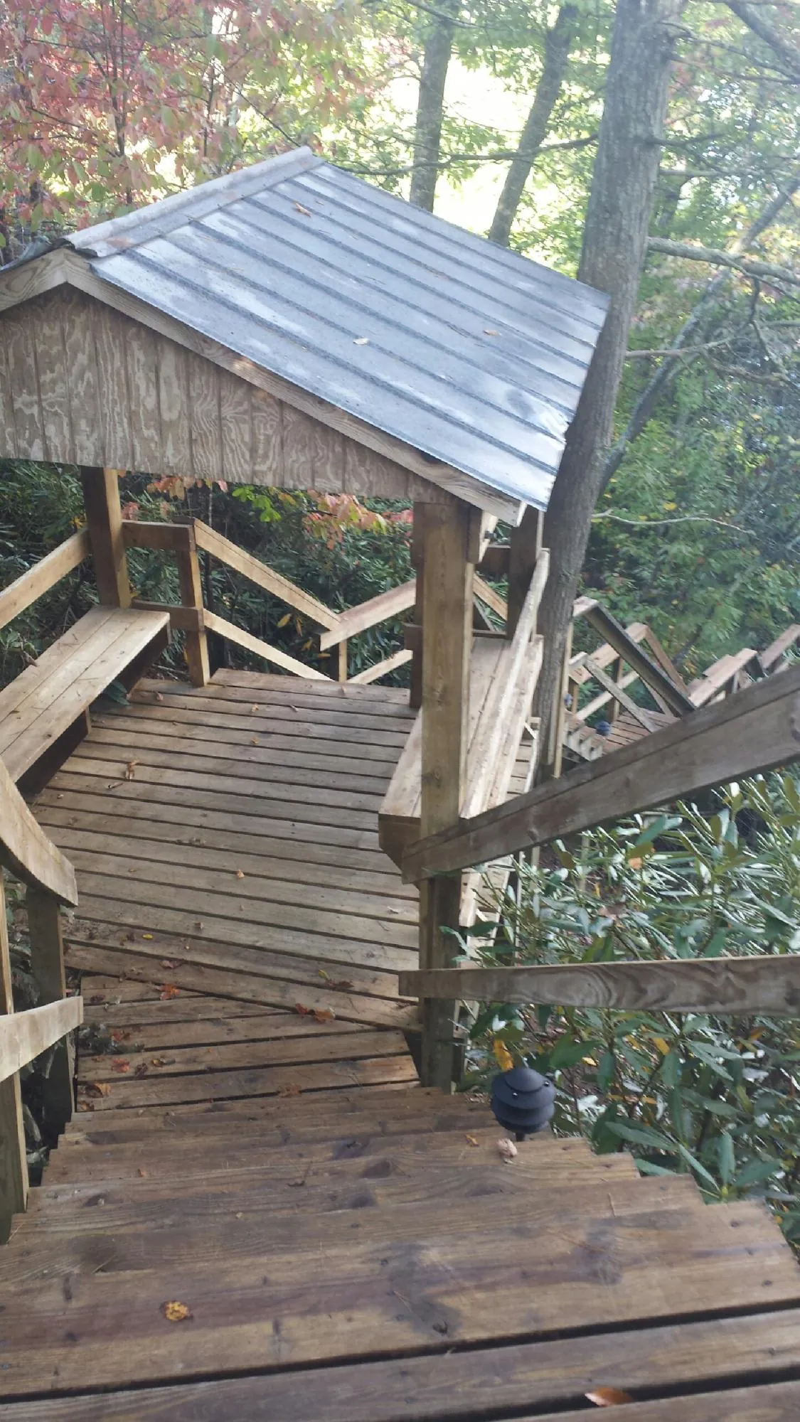 Metal roofed shelter over wooden steps on a wooded walkway — Skylight Repair & Installation work by our crew in Gill
