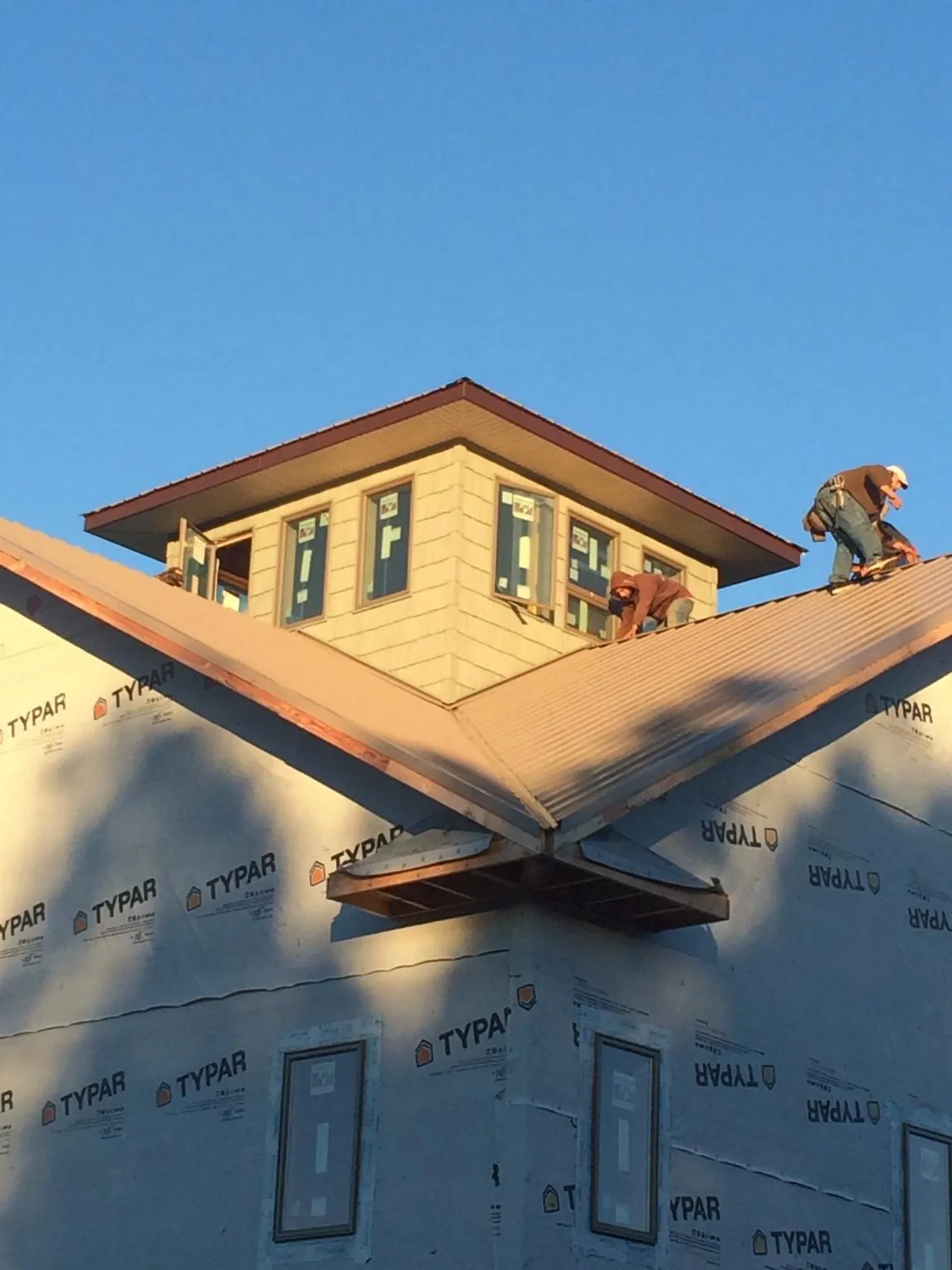 Roofers working around a rooftop cupola on a new metal roof at sunset — Roof Waterproofing in Gill by Roofing Brothers